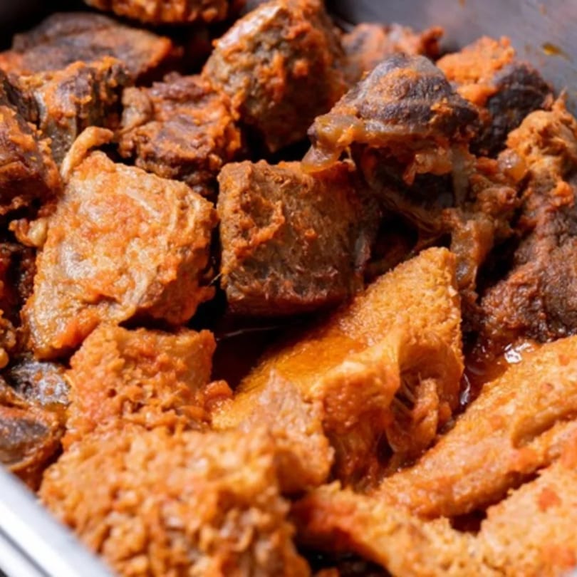 Close-up of Rodo Nigerian Cuisine's spicy stewed beef and tripe in a serving dish.
